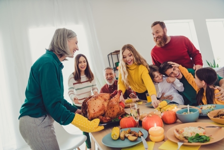 multi-generation family laughing as woman serves turkey